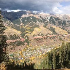 the mountains are covered with trees and houses in autumn colors, as seen from an overlook point