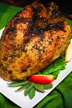 a piece of meat sitting on top of a white plate next to green leaves and tomatoes