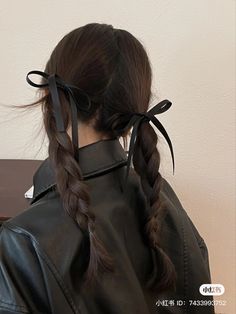 a woman with long hair wearing a black leather jacket and braids in her hair