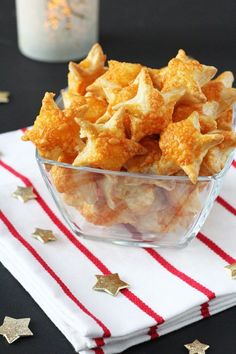 a glass bowl filled with cheetos sitting on top of a white and red napkin