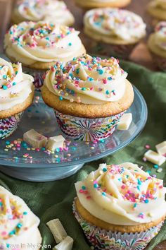 cupcakes with white frosting and sprinkles on a glass plate