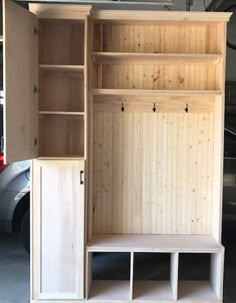 a wooden cabinet with shelves and benches in a garage next to a car parked on the street