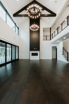 an empty room with wood flooring and chandelier hanging from the rafters