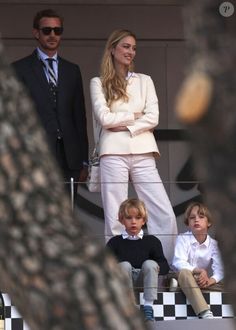 a woman and two young boys are sitting on the stands at a tennis match with their arms crossed