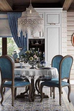 a dining room table with blue chairs and a chandelier hanging from the ceiling