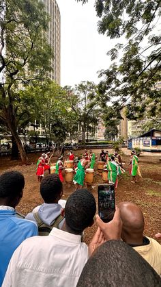 a group of people standing around each other in front of a tree filled park with musical instruments