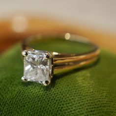 a diamond ring sitting on top of a green cushion