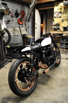 a motorcycle parked in a garage next to a wall with tools hanging on it's side