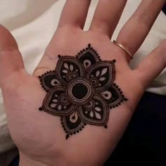 a woman's hand with a henna tattoo on the middle of her palm