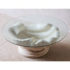 a glass table topped with white sculptures on top of a stone slabd floor next to a wall