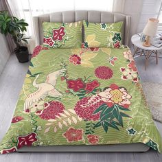 a bed covered in a green floral comforter next to a white chair and potted plant