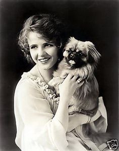 a black and white photo of a woman holding a small dog