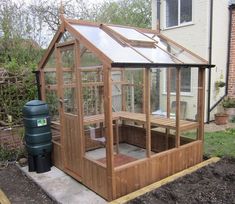 a small wooden greenhouse with a hot tub in the corner and a water tank next to it