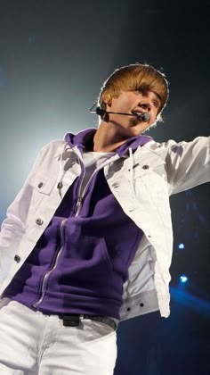 a male in a white jacket and purple shirt is holding his hands out to the side