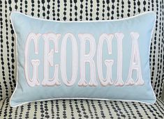 a blue pillow with the word georgia embroidered on it sitting on a patterned sofa chair