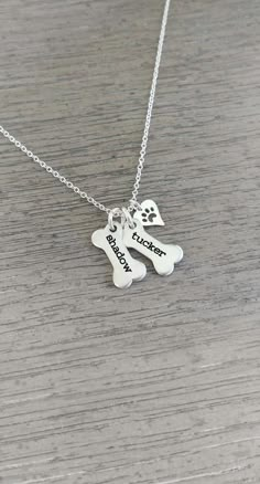 two dogs necklaces with their names on them, one is silver and the other is white