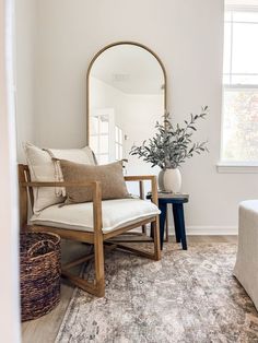 a living room with a chair, mirror and vase on the floor in front of it