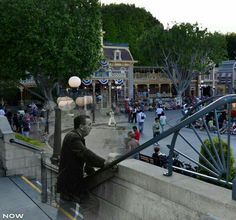 a man sitting on the side of a bridge next to a street filled with people