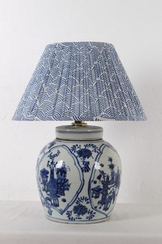 a blue and white vase with a lamp on it