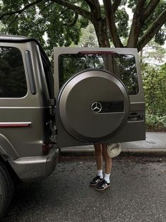 a woman is standing in front of a vehicle with the door open and her head out