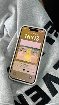 an iphone is laying on top of a hoodie with the time displayed in it