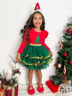 For the jolliest look, our Christmas tree tutu dress is just perfect! With ruffle details on top, a festive print, and a layered gold-lined tulle skirt, this magical number will have your little girl twinkling and twirling in delight. Finished with pom pom details for extra charm. Extra soft fabric ensures she stays comfy while looking adorably stylish too. Guaranteed to make her Santa's favorite girl!  Fully lined skirt gives her confidence to move and play. It's definitely twirl-friendly!  Perfect for holiday parties, family events, special occasions, photoshoots, and more Long-sleeve tutu dress with ruffle sleeve details, layered tulle skirt with gold lining, and Christmas tree print Available in sizes 2T-10Y Toddler Flower Girls, Dress With Ruffle Sleeves, Girls Dress Outfits, Toddler Flower Girl Dresses, Infant Flower Girl Dress, Tea Party Dress, Layered Tulle Skirt, Christening Outfit