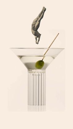 a martini glass with an olive in it and a stick sticking out of the top