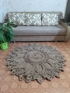 a crocheted rug on the floor next to a couch and potted plant