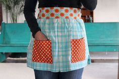 a woman wearing an apron with orange polka dots on the front and back, while she is