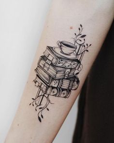 a tattoo on the arm of a woman with books and a coffee cup in it