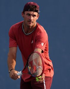 a man holding a tennis racquet on top of a tennis court with a ball in his hand