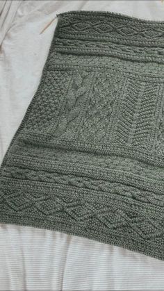 a green knitted blanket sitting on top of a bed