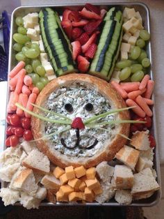 a metal tray filled with fruit and veggies next to a face made out of bread