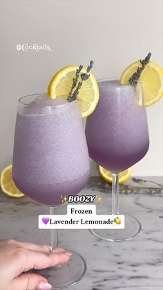 two glasses filled with lavender lemonade sitting on top of a counter