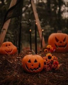 pumpkins with faces carved into them sitting on the ground in front of some candles