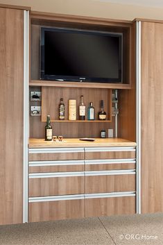 the man cave garage has an entertainment center with drawers and shelves for bottles, soaps, and other personal care items