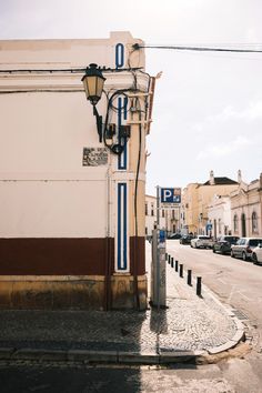 an old fashioned street light on the side of a building with cars parked in front of it