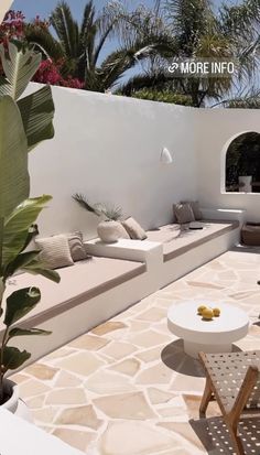 an outdoor living area with white furniture and palm trees