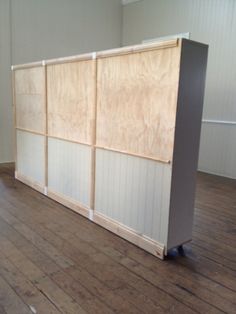 an empty room with wood flooring and white panels on the walls, along with hard wood floors