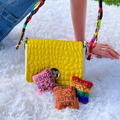 a woman's legs and hand holding a yellow purse with candy bars on it