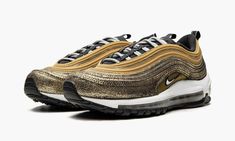 The Women’s Nike Air Max 97 “Golden Gals” nods to the golden glitz and glam of today’s creative makeup trends.  This gleaming sneaker features gold flake overlays and gold reflective material to create a shiny, luxe appearance.  Black accents are found throughout the sneaker, while a white midsole and the Air Max 97’s signature full-length Air Max tooling finish off the design Running Shoes Design, Air Max Day, Shoe Palace, Gold Sneakers, Air Max Women, Stadium Goods, Air Max 95, Nike Womens, Running Shoes Nike