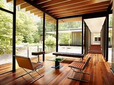 the interior of a modern house with wood floors and glass walls that overlooks trees