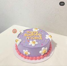 a purple birthday cake with flowers on the top and happy birthday n'kikike written on it