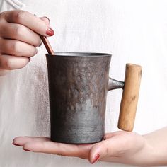 a person holding a cup with a wooden handle