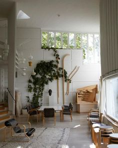 a living room filled with lots of furniture and plants on the wall next to windows