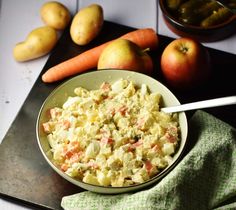 a bowl filled with potato salad next to some vegetables