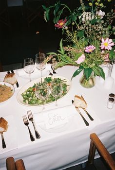 the table is set with plates and silverware, flowers in vases, and utensils