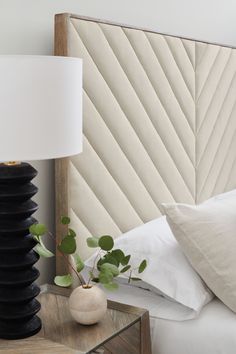 a bed with white pillows and a black lamp next to it on a night stand