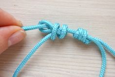 someone is holding the end of a blue rope with one knot on it and another knot in the middle