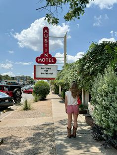 a woman is walking down the sidewalk in front of a motel sign that reads aussie motel